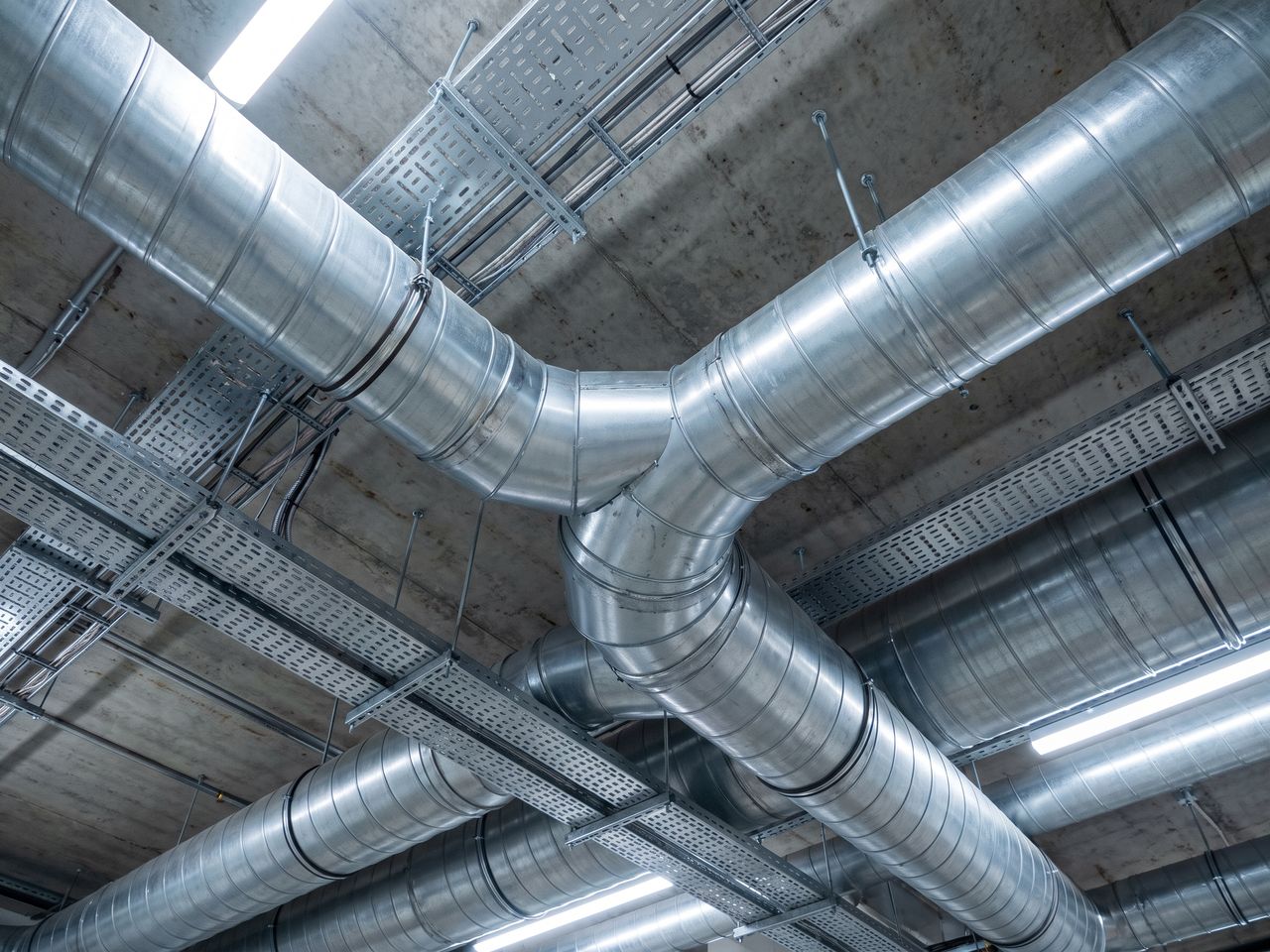 Vertakt gegalvaniseerd ventilatiekanaal onder een betonnen plafond